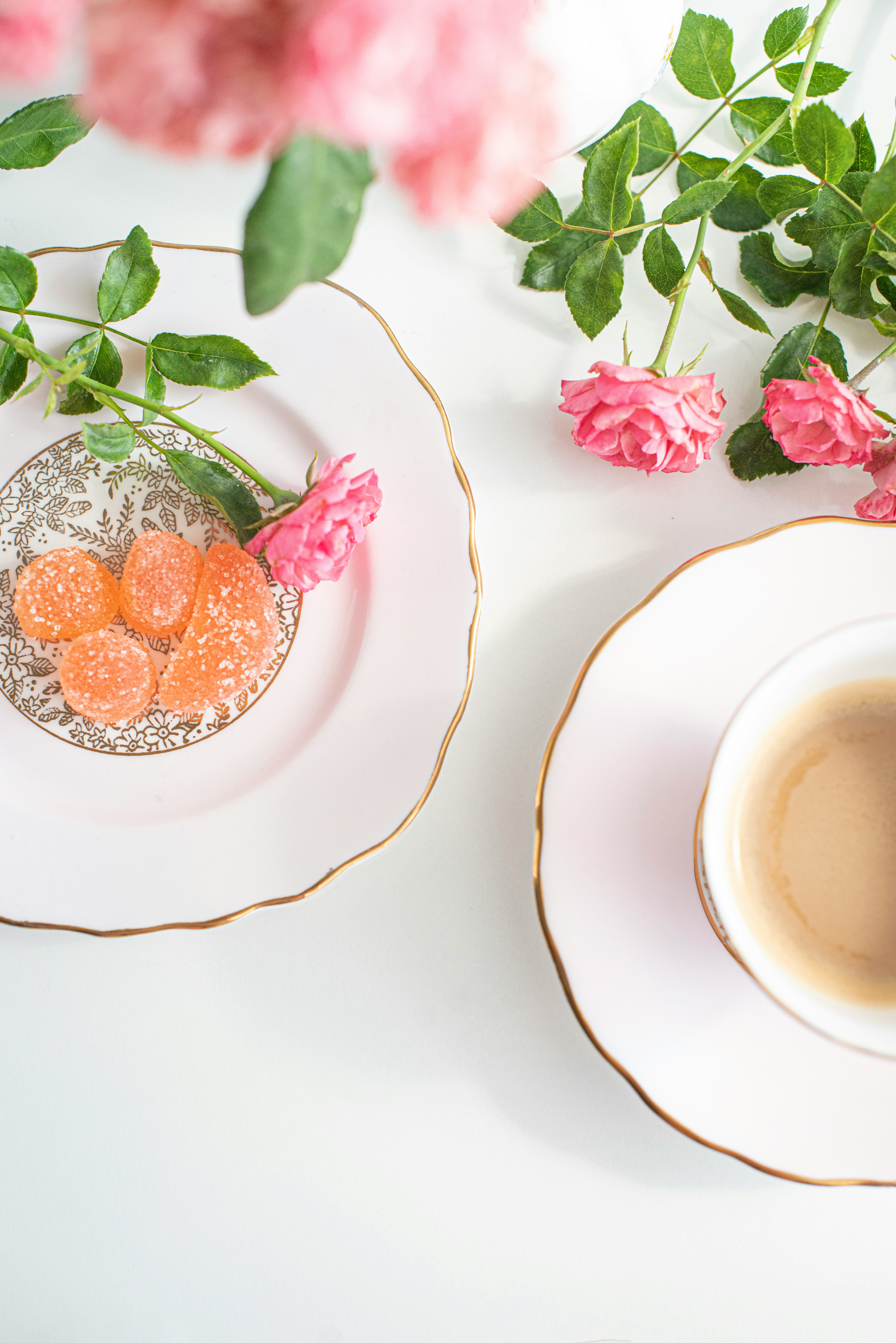 white ceramic cup with saucer beside pink flowers